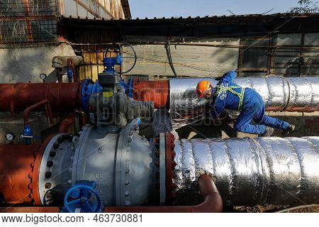Bucharest, Romania - October 13, 2022: Worker Uses Glass Wool To Thermal Insulate A Hot Water Metall