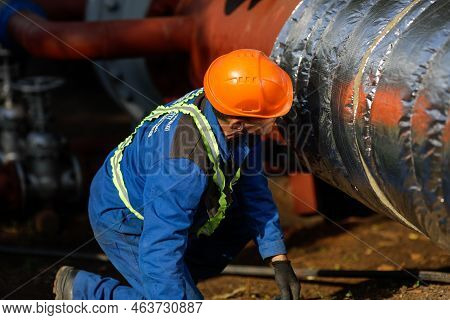 Bucharest, Romania - October 13, 2022: Worker Uses Glass Wool To Thermal Insulate A Hot Water Metall