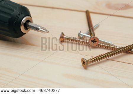 Table With Tool. Electric Screwdriver On A Wooden Table. Side View Of The Black Metallic Screws, Ele