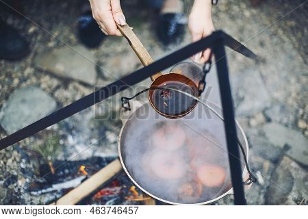 From Above Traditional Mulled Wine With Slices Of Orange Preparing In Pot Over Burning Logs In Winte