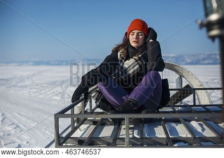 Baikal Lake In February. Female Tourists Travel On A Hivus Hovercraft Through The Frozen Small Sea S