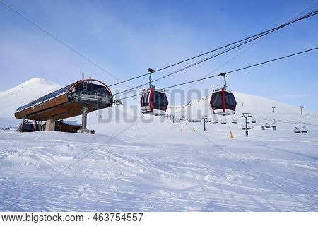 Cable Car Gondola At Ski Resort With Snowy Mountains On Background. Modern Ski Lift With Funitels An