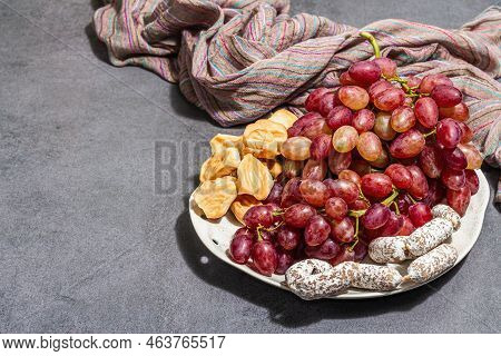 Snack Plate With Cheese, Grapes And Dried Sausages. Charcuterie Antipasto, Stone Concrete Background