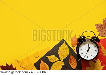 Daylight Saving Day. Fall Back. Black Alarm Clock And Autumn Leaves On Yellow Background. Daylight S