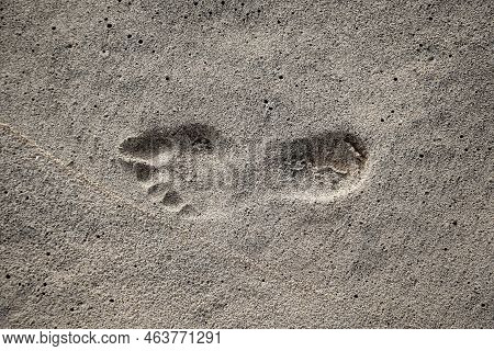 The Footprint Of A Person In The Wet Sand On The Beach.