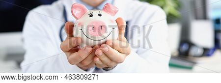Portrait Of Man Doctor Hold White Piggy Bank, Message To Saveup Money For Healthcare. Doctor Support