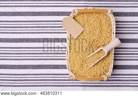 Traditional Dry Pearl Couscous In A Wicker Basket On A Textile Background. Top View.
