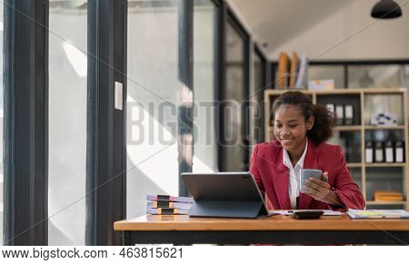 Smiling Young African American Female Finance Entrepreneur Sitting In Workplace Office Hoding Coffee