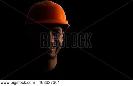 Dirty Face Of Coal Miner On A Black Background. Head Of Tired Mine Worker In A Hard Hat.