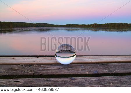 Glass Ball On A Wooden Pier At A Swedish Lake At Evening Hour. Nature Shot From Scandinavia
