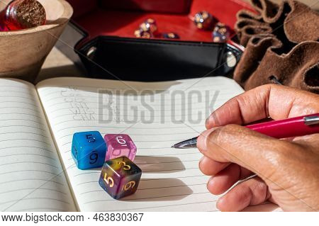 Close-up Image Of Someone Of Color Writing Down Character Modifier For A Tabletop Role-playing Game