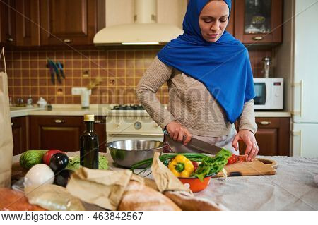 Charming Middle-eastern Muslim Woman, Pretty Housewife In Blue Hijab, Standing By A Kitchen Table, C
