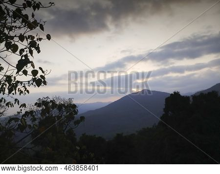 Sunset Seen From Viewpoint With Cluody Sunset Sky, Distant Mountains In The Background And Forest In