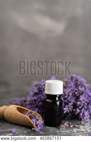Glass Bottle Of Lavender Essential Oil With Wooden Scoop Of Lavender Flowers On Wooden Scoop, Aromat