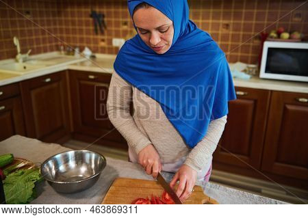Beautiful Middle Eastern Muslim Woman, Pretty Housewife With Head Covered In Blue Hijab, Chopping Or