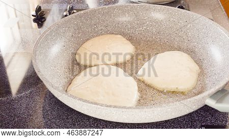 Frying Pancakes In A Frying Pan Over The Electric Stove.