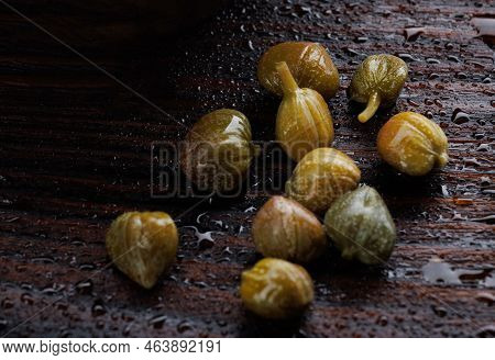 Pickled Capers Lie On A Wooden Board.