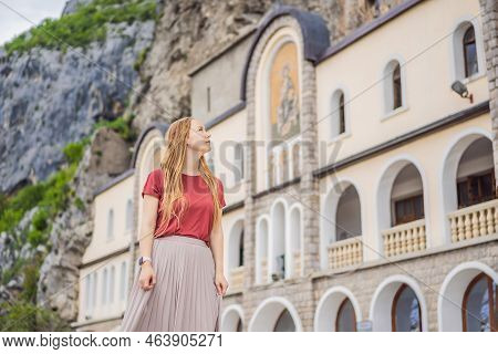 Woman Tourist In Monastery Of Ostrog, Serbian Orthodox Church Situated Against A Vertical Background