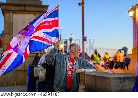 London - September 17, 2022: Man Holds Union Jack Flag With Queen's Face On It In Early Evening Ligh