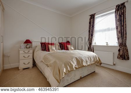 Stradishall, Suffolk, England - June 1 2017 Furnished Bedroom With Red And Gold Coloured Cushions.