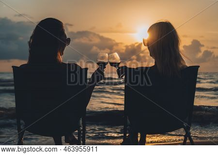 Silhouette Of Two Sexy Young Women In Sunglasses And Bikinis Sitting On Folding Chairs On The Seasho