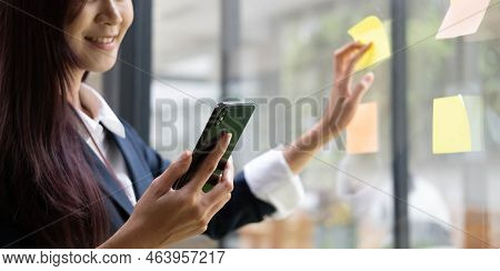 Close-up Of A Woman Hand Holding A Pen Affixing A Note To Her Mirror At The Office.