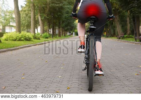 Problem Of Injured Coccyx. Woman Riding Bicycle On Road