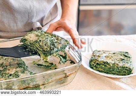 Woman's Hands Putting One Porzione Of Homemade Lasagna With Spinach And Ricotta In White Plate From 