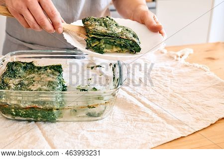 Woman's Hands Putting One Porzione Of Homemade Lasagna With Spinach And Ricotta In White Plate From 