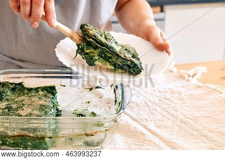 Woman's Hands Putting One Porzione Of Homemade Lasagna With Spinach And Ricotta In White Plate From 