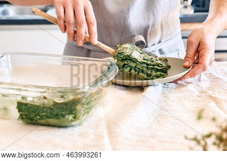 Woman's Hands Putting One Porzione Of Homemade Lasagna With Spinach And Ricotta In White Plate From 