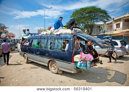 NEAK LEUNG, CAMBODIA - NOV 19, 2013: Passengers sit atop a very overloaded vehicle in Neak Leung on Noveber 17, 2013, Cambodia. This kind of domestic transportation carries between 16 to 30 passengers.