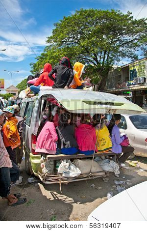 NEAK LEUNG, CAMBODIA - NOV 19, 2013: Passengers sit atop a very overloaded vehicle in Neak Leung on Noveber 17, 2013, Cambodia. This kind of domestic transportation carries between 16 to 30 passengers.