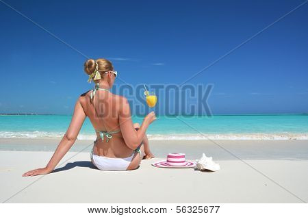 Girl with a glass of orange on the beach of Exuma, Bahamas 