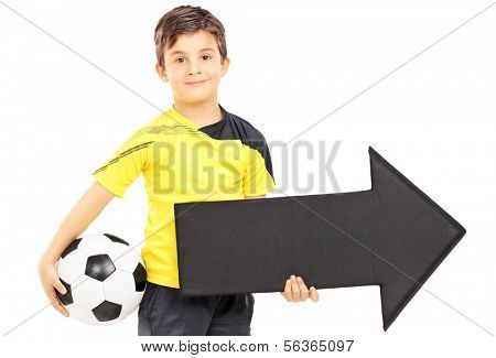 Smiling boy in sportswear holding a soccer ball and black arrow pointing right isolated on white background