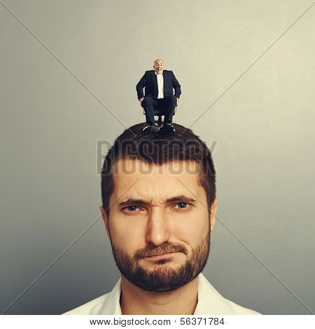 portrait of displeased man with small boss on the head