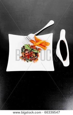 vegetable salad : cherry tomatoes and basil with sweet baked potato served on white plate with sauceboat full blask soy sauce on wood