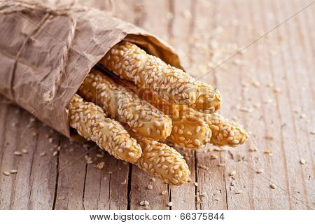 bread sticks grissini with sesame seeds in craft pack on rustic wooden background