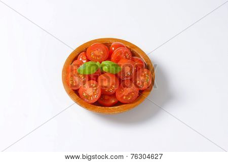 overhead view of bowl with halved cherry tomatoes decorated with basil