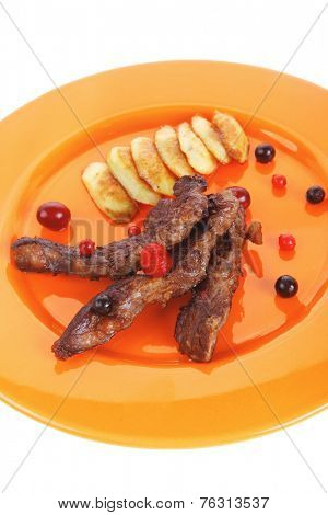 grilled beef meat with berries fried potatoes and cherry under sweet honey sauce on orange plate isolated over white background