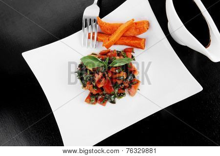 vegetable salad : cherry tomatoes and basil with sweet baked potato served on white plate with sauceboat full blask soy sauce on wood