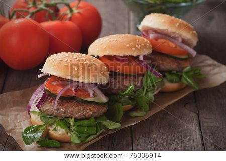 Mini hambugers with tomato and onion on wooden table