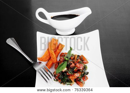 vegetable salad : cherry tomatoes and basil with sweet baked potato served on white plate with sauceboat full blask soy sauce on wood