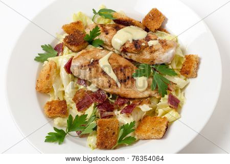 Chicken caesar salad, grilled chicken breast on a bed of lettuce tossed in a parmesan flavoured garnished with croutons, bacon bits and italian flat-leaf parsley.