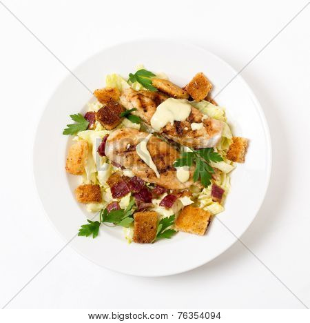 Chicken caesar salad, grilled chicken breast on a bed of lettuce tossed in a parmesan flavoured garnished with croutons, bacon bits and italian flat-leaf parsley.