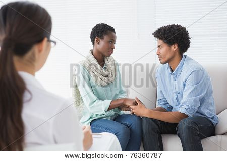 Reconciled couple smiling at each other in therapists office