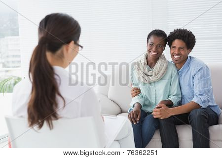 Reconciled couple smiling at their therapist in therapists office