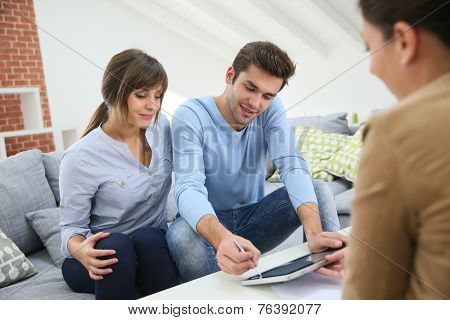 Young couple signing financial contrat on digital tablet