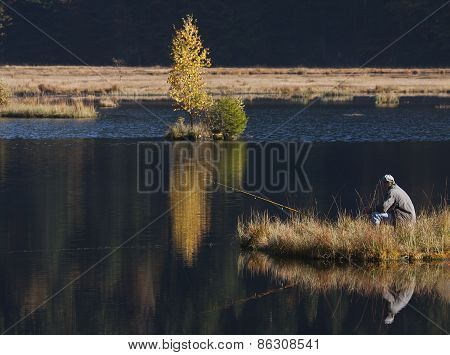 fisherman fishing at Lispach lake, Vosges, France
