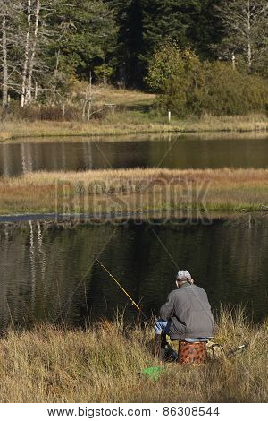 fisherman fishing at Lispach lake, Vosges, France